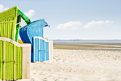 Zwei Strandkörbe am Sandstrand, Meer und blauer Himmel im Hintergrund