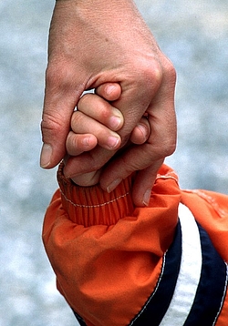 Nahaufnahme von einer Kinderhand und einer Erwachsenenhand, die sich halten