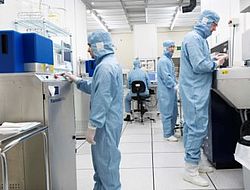 Vier Menschen in Ganzkörperschutzänzügen arbeiten in einem sterilen Labor