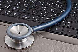 Nahaufnahme: Stethoskop liegt auf einer Laptoptastatur