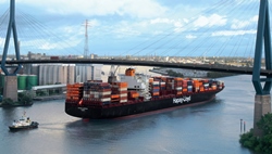 Großes Containerschiff fährt unter einer Brücke hindurch